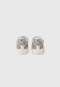 Hvide sneakers med et mønster i sort linjekunst på bagsiden, med en struktureret sål og polstret krave for komfort.