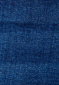 Tela de mezclilla azul oscuro con una textura suave, que presenta un patrón de sarga clásico y fibras claras en contraste a lo largo de toda la superficie.