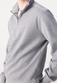 Gray quarter-zip pullover made of textured fabric, featuring contrasting shoulder accents and ribbed cuffs. Zipper detail at the neck.