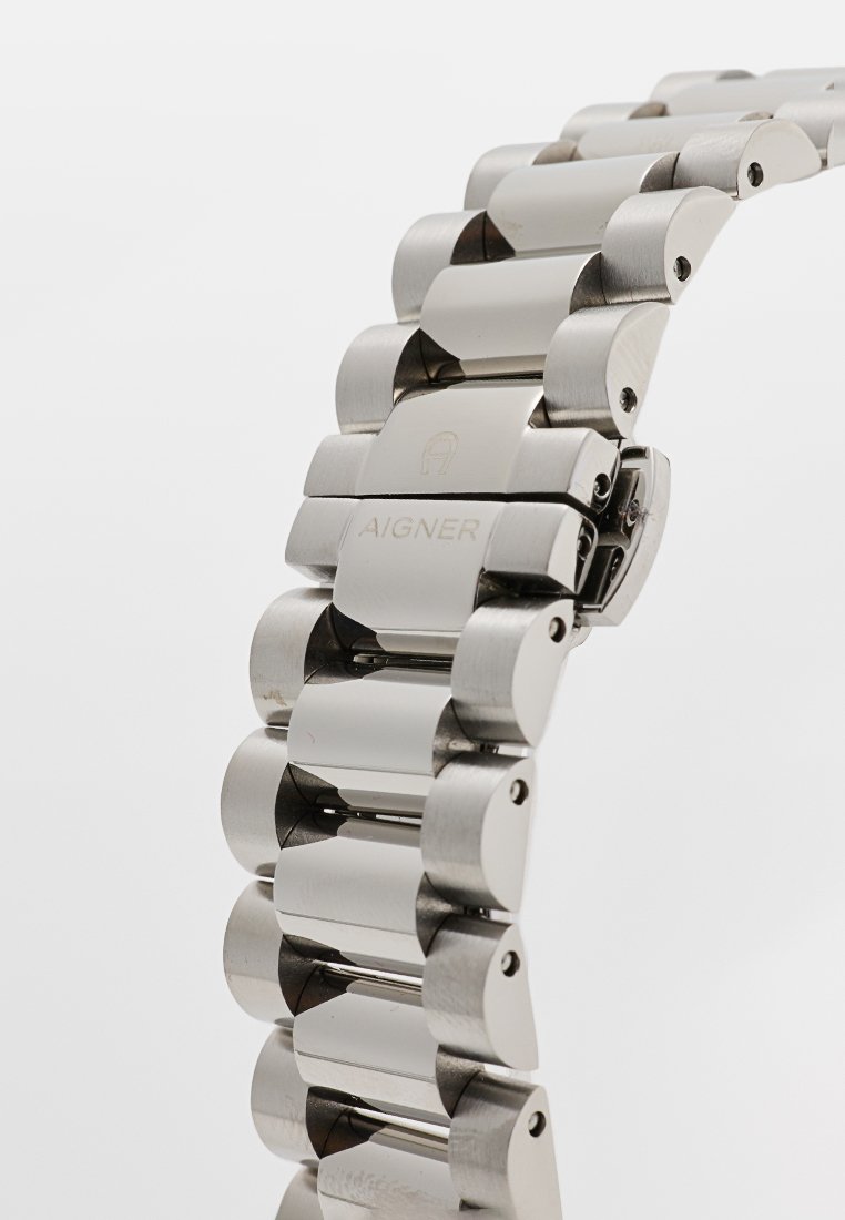 Silberner Edelstahl-Uhrenarmband mit runden Gliedern, ausgestattet mit einer polierten Oberfläche und geprägtem "AIGNER"-Logo auf einem Glied.