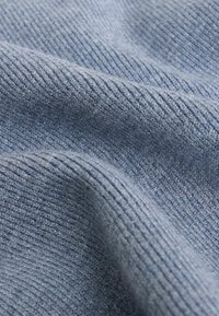 Light blue textured fabric with ribbed pattern, featuring soft fibers and subtle sheen, draped in gentle folds.