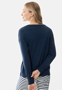 Marineblauwe long-sleeve shirt van zachte stof met een relaxte pasvorm, met verlaagde schouders. Gecombineerd met witte en marineblauwe gestreepte broeken.