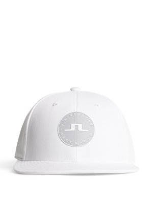 White baseball cap with a flat brim and a round silver logo patch featuring "J. LINDEBERG STOCKHOLM." Smooth fabric texture, slightly structured.