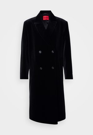 Melns samta divrindas mētelis ar izgrieztu apkakli, garām piedurknēm, divām priekšējām kabatām un spilgti sarkanu iekšējo etiķeti.