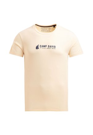 Beige cotton t-shirt with short sleeves and a crew neck. Features a dark blue printed logo and text: "CAMP DAVID IT'S ALL ABOUT WIND."