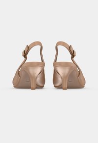 Λουστρίνι γόβες slingback σε γυμνό χρώμα με στρογγυλεμένη μύτη, ρυθμιζόμενο λουράκι στον αστράγαλο και μέτριο τακούνι στιλέτο. Ομαλή υφή, μινιμαλιστικός σχεδιασμός.