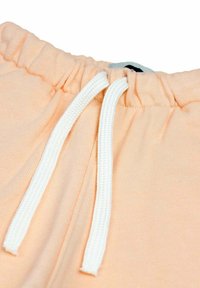 Perzikkleurige joggingbroek met een zachte textuur, elastische tailleband en witte trektouwtjes voor aanpassing. Minimalistisch ontwerp, geen patronen.