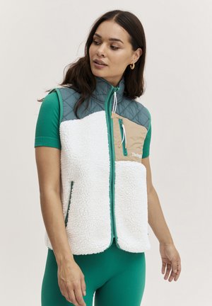 Fleece vest med en myk hvit kropp, grønne detaljer og en quiltet grå overdel. Har glidelåslomme og justerbar snor.