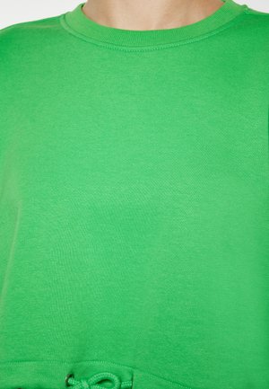 Zöld pamut pulóver kerek nyakkivágással, texturált anyaggal és zsinóros részlettel az alján. Simább felület, laza kialakítás.