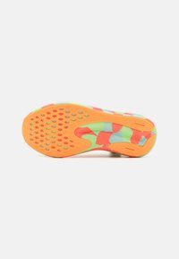 Suela de una zapatilla deportiva con un patrón de camuflaje multicolor en naranja, verde y azul, que presenta agarres circulares y una superficie de goma texturizada.