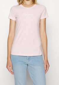 Světle růžové bavlněné tričko s krátkými rukávy a kulatým výstřihem. Na přední straně je bílé logo "Pepe Jeans London".