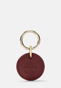 Portachiavi rotondo in pelle bordeaux con logo ad albero in rilievo, attaccato a un anello in metallo dorato per una chiusura sicura.
