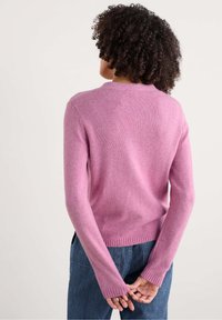 Roze wollen trui met een slim fit, ronde halslijn, geribbelde manchetten en rand. Heeft een gladde textuur en iets langere mouwen bij de polsen.