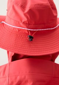 Chapeau seau rouge à large bord, avec un cordon de serrage rose contrastant et un toggle ajustable. Fabriqué en matériau lisse et léger.