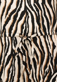 Ύφασμα με ρίγες ζέβρας σε μαύρο, καφέ και μπεζ, με δεμένο φιόγκο στη μέση ενός ενδύματος.