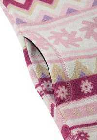 Strickstoff mit rosa, lila und beigen geometrischen und floralen Mustern an einer Ärmelnäht mit sichtbaren Stichdetails.