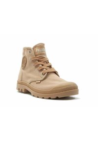 Scarpe high-top in tela beige con suola in gomma, punta tonda e lacci frontali. Presentano una patch con logo sul lato e una etichetta bianca a contrasto sulla linguetta.