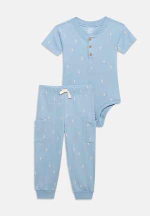 Bodysuit azul claro de manga corta para niño pequeño con botones y pantalones a juego que cuentan con bolsillos y pequeños estampados de rayos blancos.