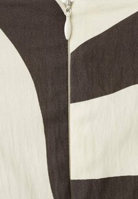 Tela de algodón con un audaz patrón abstracto en negro y crema, con un cierre central y bordes redondeados. Material texturizado y resistente.