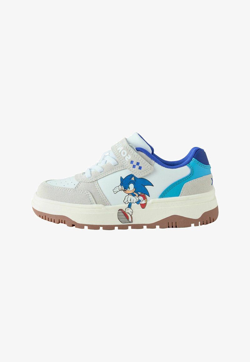 Baskets blanches avec détails en daim beige, doublure intérieure bleue et illustration de Sonic the Hedgehog sur le côté avec une semelle en caoutchouc marron.