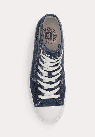 Navy blue canvas sneaker with white rubber toe, white laces, visible stitching, and Ralph Lauren logo on the insole.