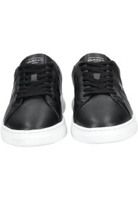 Schwarze Leder-Sneaker mit glatter Oberfläche, weißer Gummisohle und flachen schwarzen Schnürsenkeln. Mit Branding auf der Zunge und an den Seiten.