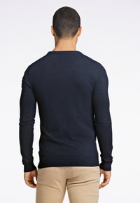 Granatowy sweter z długimi rękawami, wykonany z gładkiego dzianinowego materiału, z okrągłym dekoltem i dopasowanym krojem, wykończony prążkowanymi mankietami.