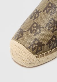 Εσπαντρίγια με καφέ υφασμάτινο επάνω μέρος που φέρει το λογότυπο "DKNY", σε φινίρισμα με φυσική σόλα από ψάθα και υφαντή υφή στο σημείο των δαχτύλων.