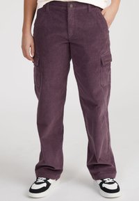 Purple corduroy cargo pants feature a relaxed fit, two side pockets, and a front button closure. Worn with black and white sneakers.