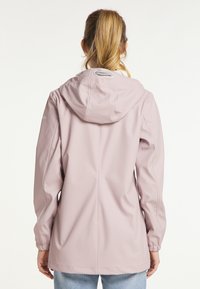 Veste imperméable rose clair avec capuche, poignets élastiques et texture lisse. Dotée d'un cordon de serrage à l'arrière pour ajustement.