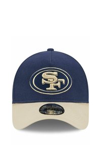 Marineblaue Mütze mit einem beigen Schirm, versehen mit einem gestickten SF-Logo in Gold auf der Vorderseite. Hergestellt aus Stoff mit einer strukturierten Oberfläche.