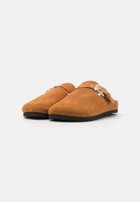 Chaussures marron en daim à enfiler avec une texture lisse, bout rond et une boucle métallique décorative. Semelle en caoutchouc noire pour une adhérence optimale.