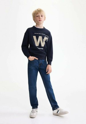 Felpa navy con testo bianco e oro, inclusi 'W' e 'WEEKEND', abbinata a jeans blu e sneakers grigie con dettagli a righe.