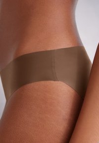 Braune nahtlose Unterwäsche mit einem breiten, glatten Bund. Der Stoff sieht weich und dehnbar aus und harmoniert gut mit dem Hautton.