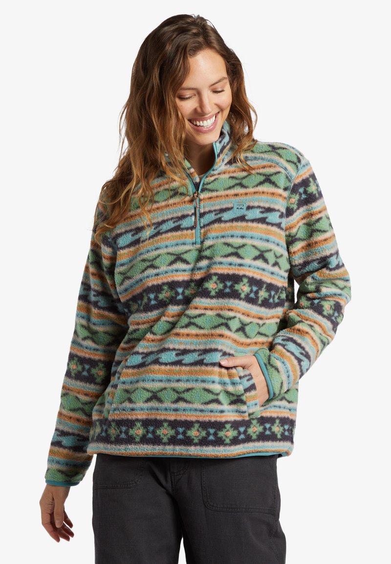 Fleece pullover met een ritskraag, gekenmerkt door een intricaat groen, oranje en marineblauw geometrisch patroon. Rond gesneden zoom en zijzakken inbegrepen.