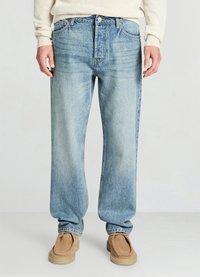 Hellblaue Jeans aus Denim mit entspannter Passform, verblasster Textur, geraden Beinen und klassischem Fünf-Taschen-Design. Kombiniert mit beigen Slippern.