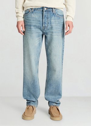 Jean en denim bleu clair avec une coupe décontractée, une texture délavée, des jambes droites et un design standard à cinq poches. Associé à des chaussures beige à enfiler.