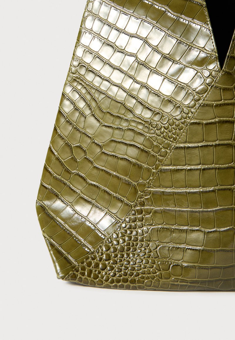 Sac à main vert olive en simili-crocodile texturé, présentant un design géométrique avec des échelles variées et une finition brillante.