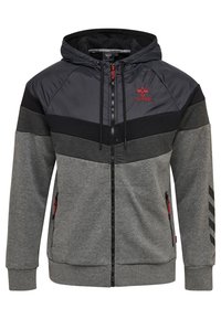 Hættetrøje med lynlås i grå og sort, med polstret øverste sektion, røde detaljer og sidelommer. Tekstureret stof med fiskebenmønster.