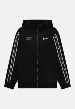 Svart zip-up hoodie med huva, med vita Nike-logotyper på bröstet och ärmarna, samt vita detaljer längs sidorna. Mjuk tyg.