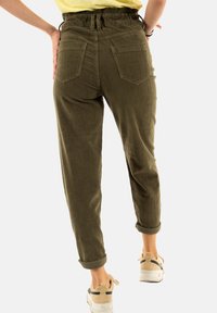 Pantalons en velours côtelé vert olive avec une coupe décontractée, taille élastique, poignets retroussés et deux poches arrière, présentant une texture côtelée verticale.
