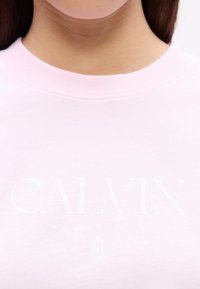 Lyserød sweatshirt lavet af blød bomuld, med "CALVIN KLEIN" logoet trykt i hvidt, rund halsudskæring og enkel syning.