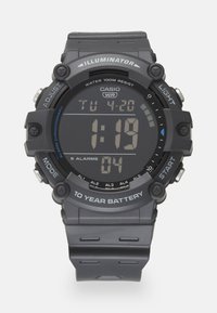 Montre digitale Casio avec un bracelet en résine gris, écran LCD, étanchéité jusqu'à 100 mètres, et fonctionnalités pour alarmes et rétroéclairage.