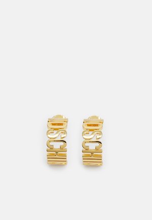 Goudkleurige metalen oorknopjes met uitsnedes die de letters van "MOSCHINO" verticaal vormen.