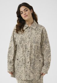 Leopard-print jacket made of lightweight fabric, featuring a collared neckline, long sleeves, and two front pockets. Color is beige with black spots.
