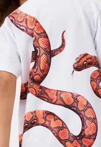 Weißes Baumwoll-T-Shirt mit großem, buntem Grafikdruck eines roten und schwarzen Schlanges, die sich über den Rücken windet und Details der Schuppen zeigt.