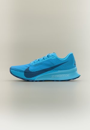 Chaussure de course Nike ZoomX bleue avec logo swoosh noir et design à lacets sur fond neutre.