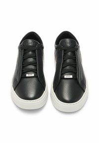 Par de zapatillas negras de cuero texturizado con suelas blancas, cordones negros y etiquetas metálicas "BOSS" en la parte delantera de los cordones.
