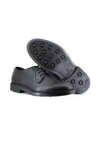 Scarpa elegante nera in pelle con punta rotonda, design stringato e suola in gomma testurizzata con pattern circolari di presa.