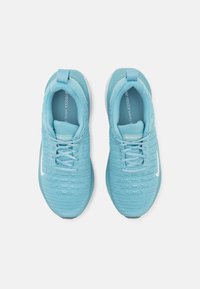 Vaaleansiniset urheilukengät, joissa on teksturoitu neulepinta, nauhakiinnitys, pehmustettu varsi ja valkoinen kumipohja. Sivussa on Nike-logo.